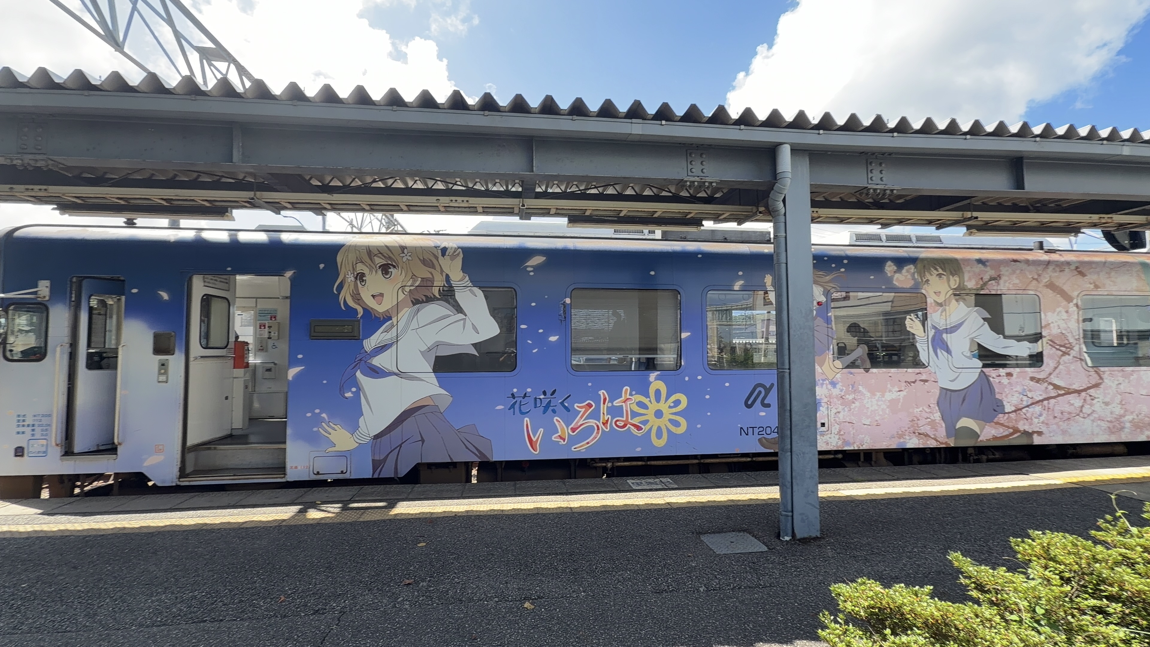 七尾駅のとホームに停まるラッピング列車「花咲くいろは」、セーラー服の女の子と桜の花びらが描かれた車体