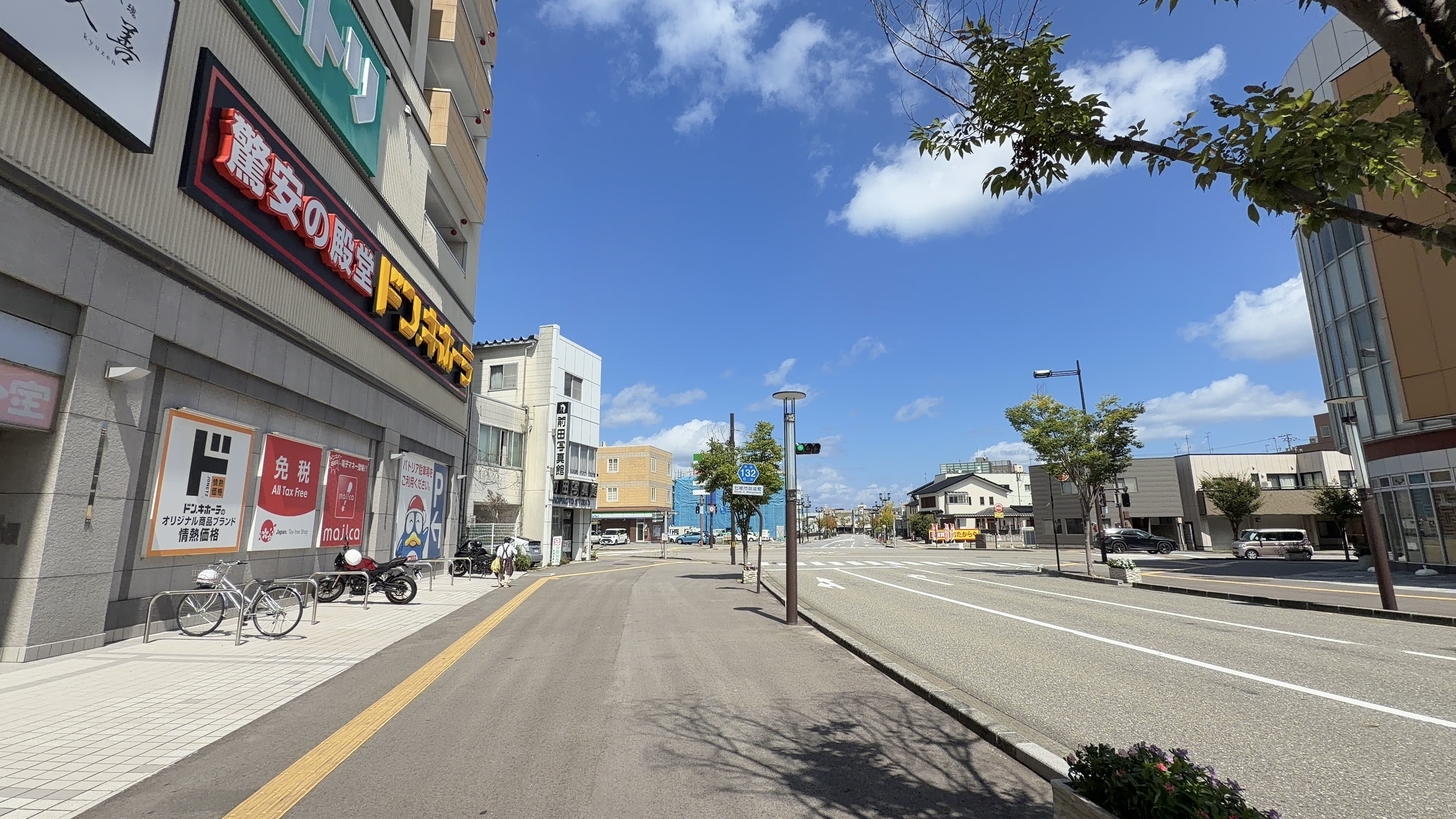 大型商業ビル「パトリア」の外観、「驚安の殿堂 ドン・キホーテ」とニトリの看板、県道132の標識が見える通り