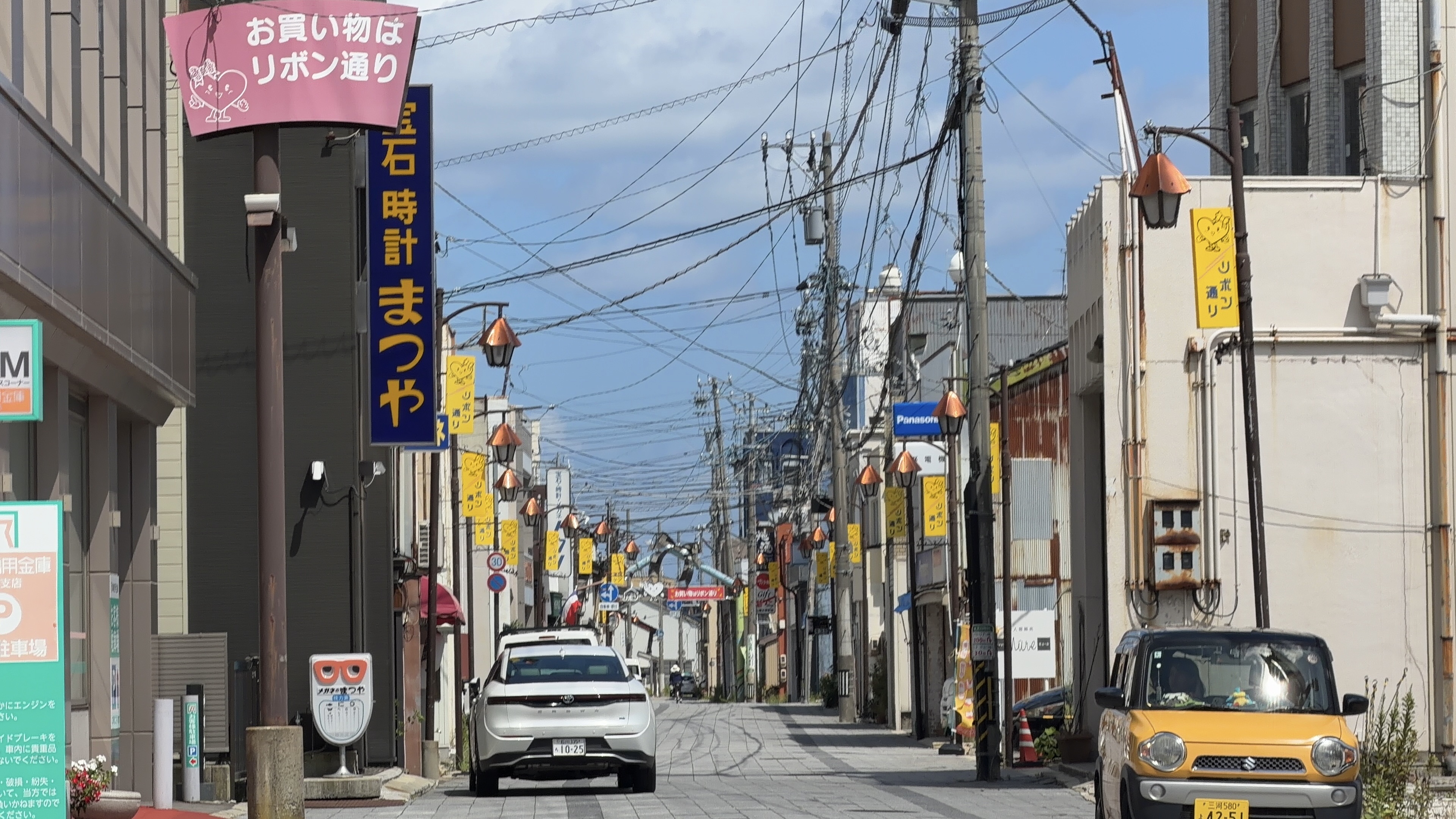 リボン通り商店街のアーケード、両脇に連なる吊り看板と提灯、電線が交差する空