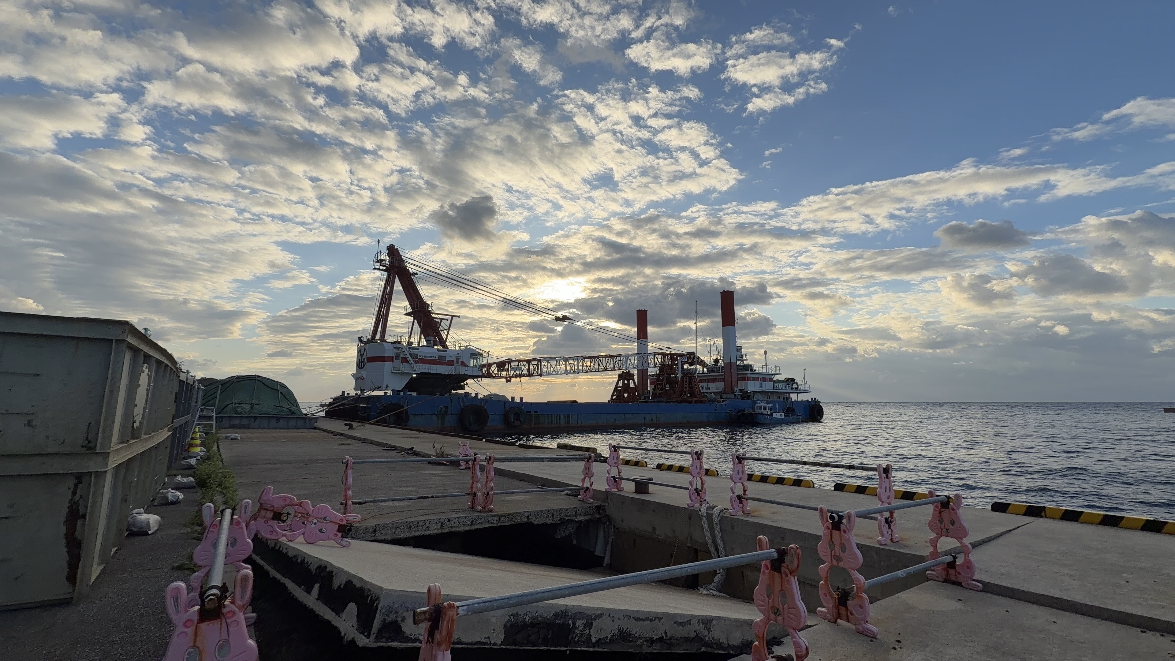 小木港「劇場」の朝、大きなクレーン船と朝焼けの空