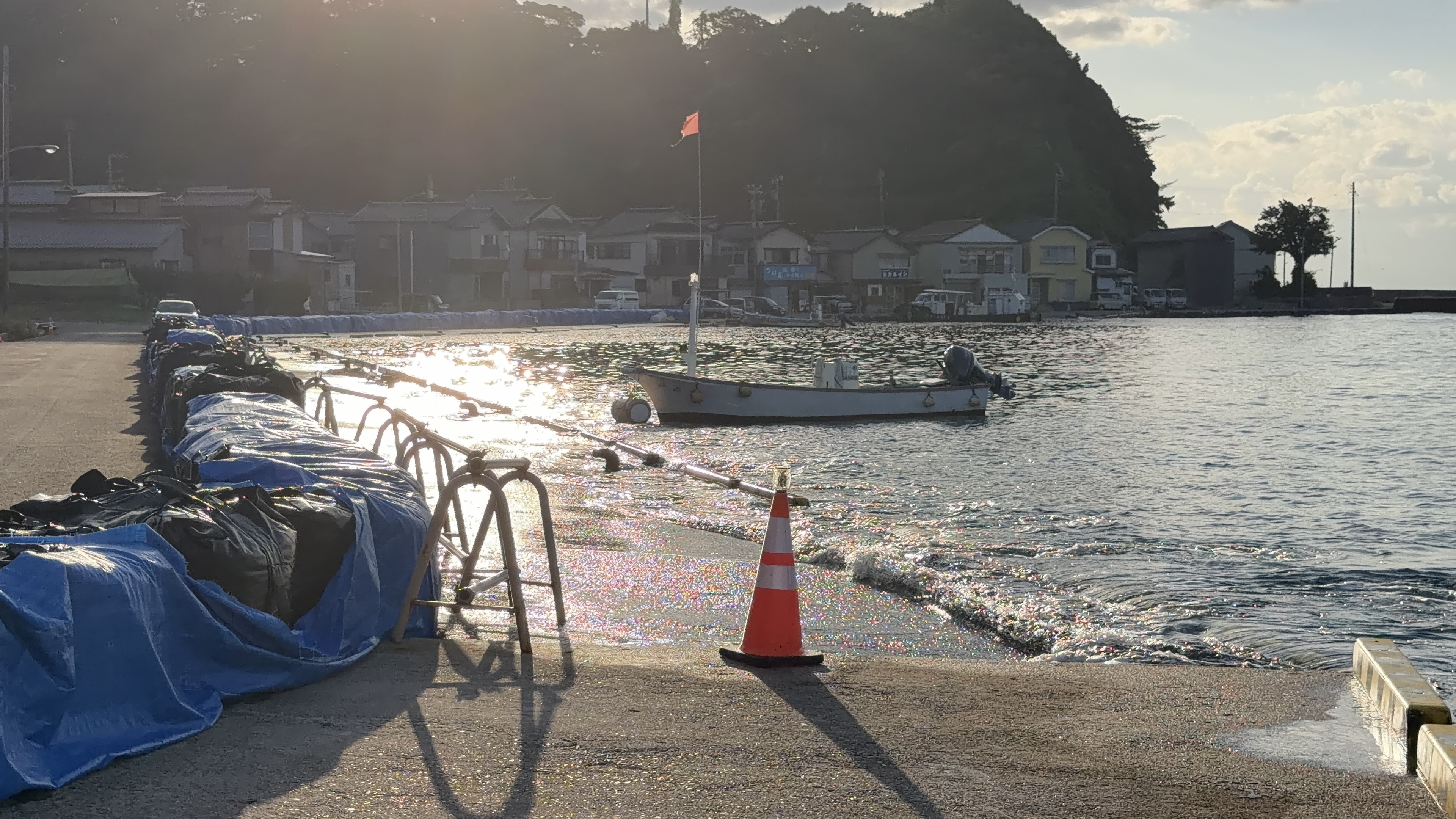 逆光にきらめく水面と、朝日を浴びる漁船