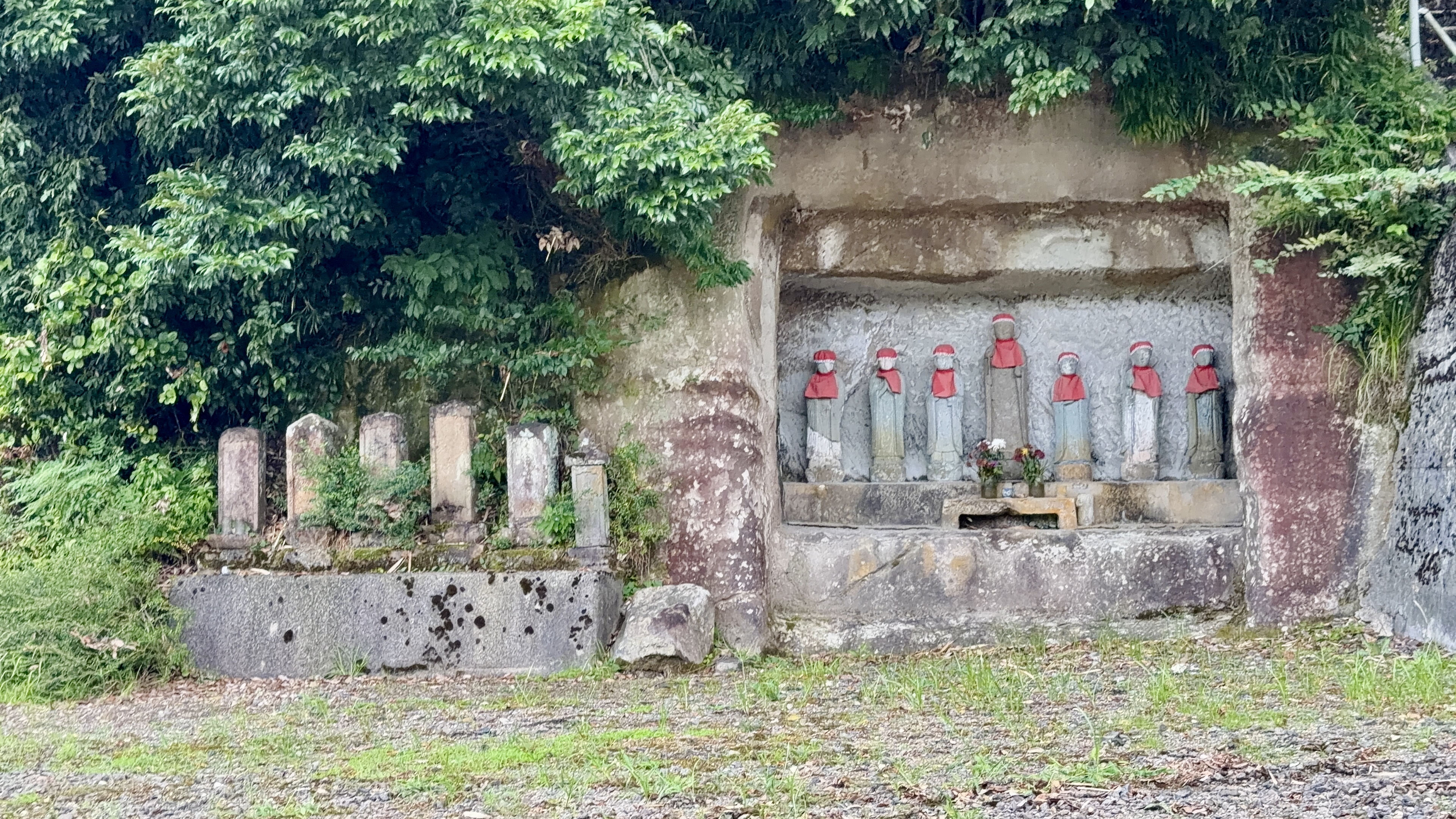 岩をくりぬいた祠に並ぶ、赤い前掛けの七体のお地蔵様