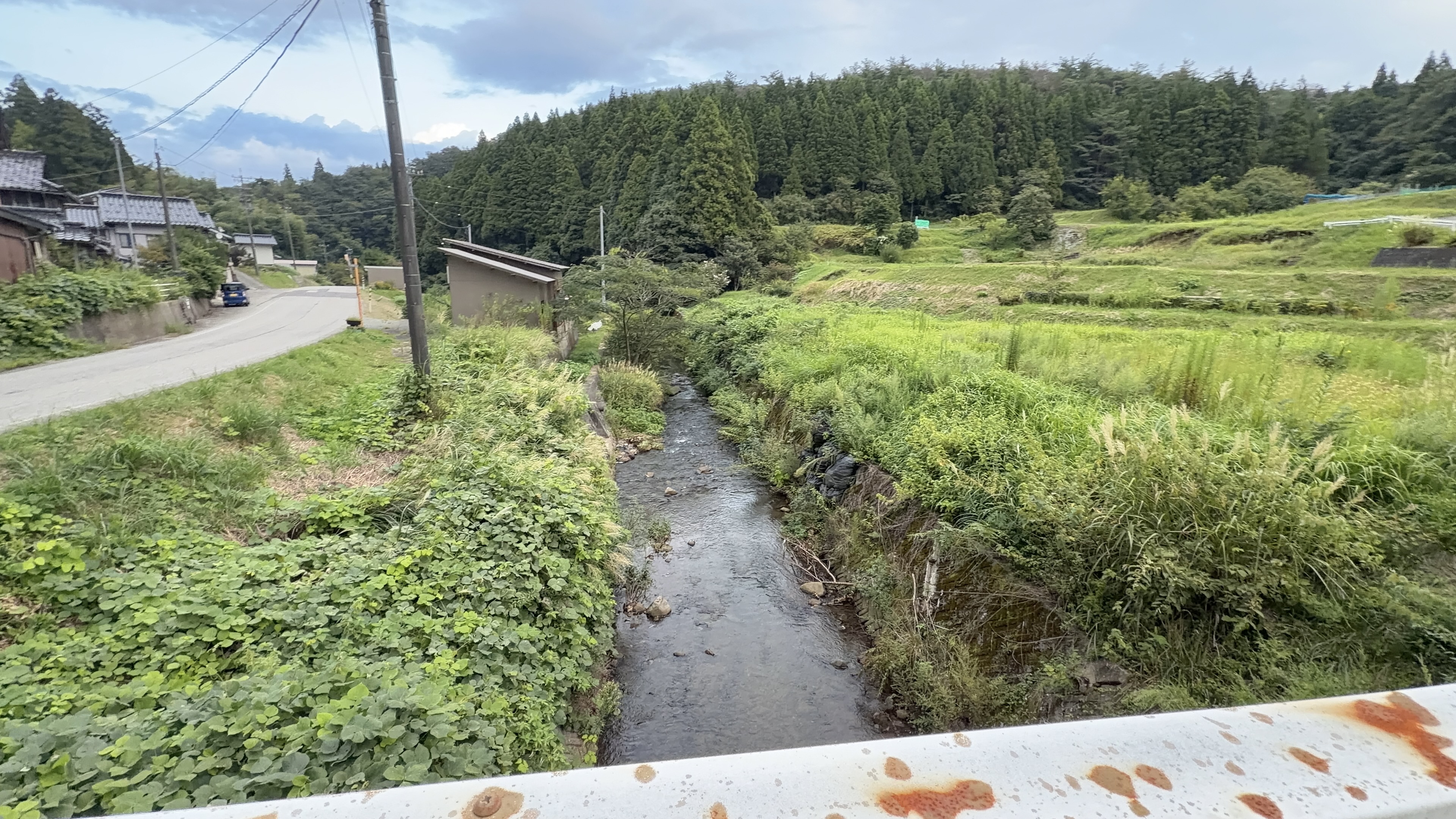 山あいの小さな集落を見下ろす夕方の景色、曇り空の下に瓦屋根の家が点在する