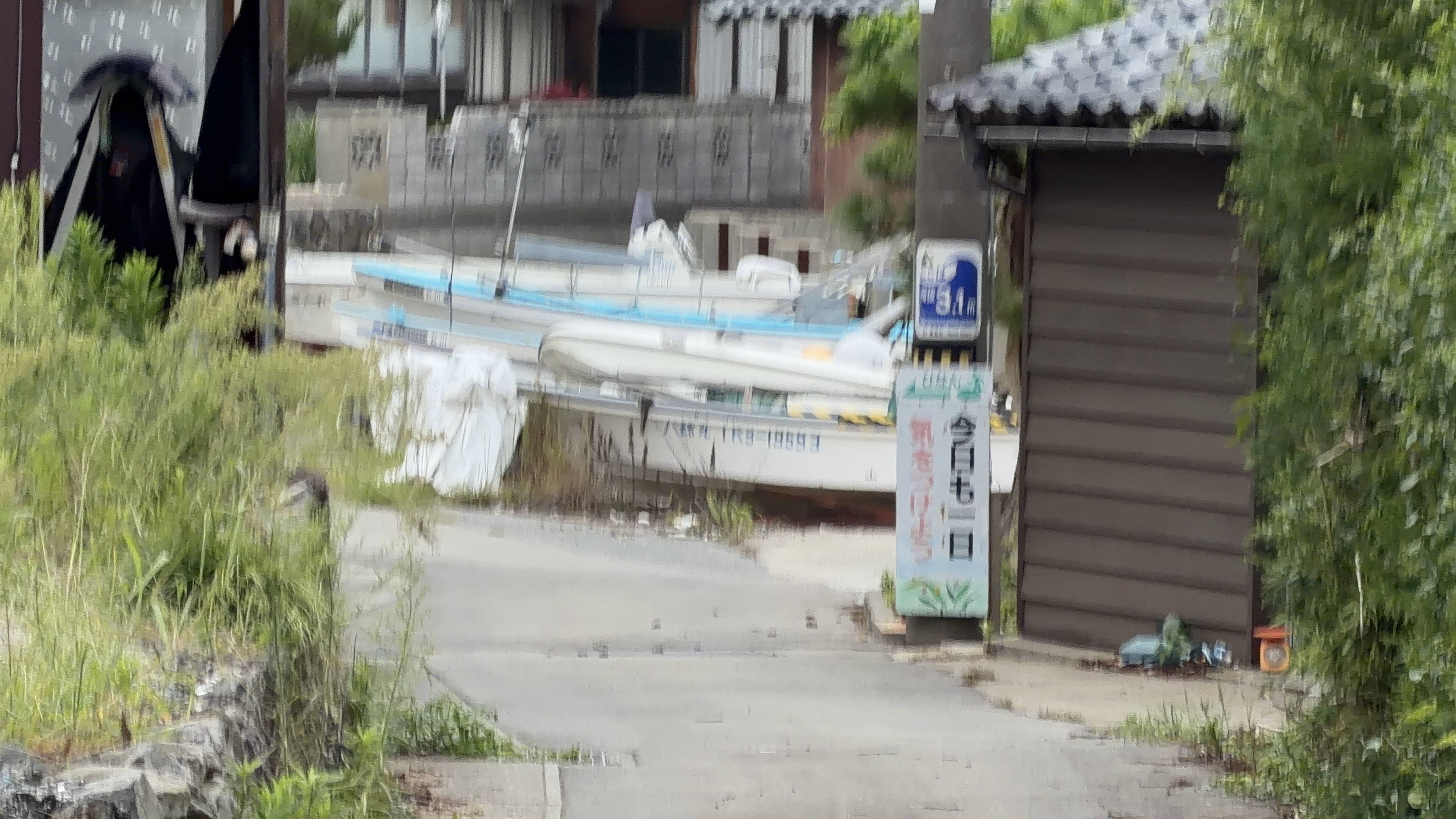 ズームでぼやけた港の風景、白いボートが並び、青い標識の柱が立つ
