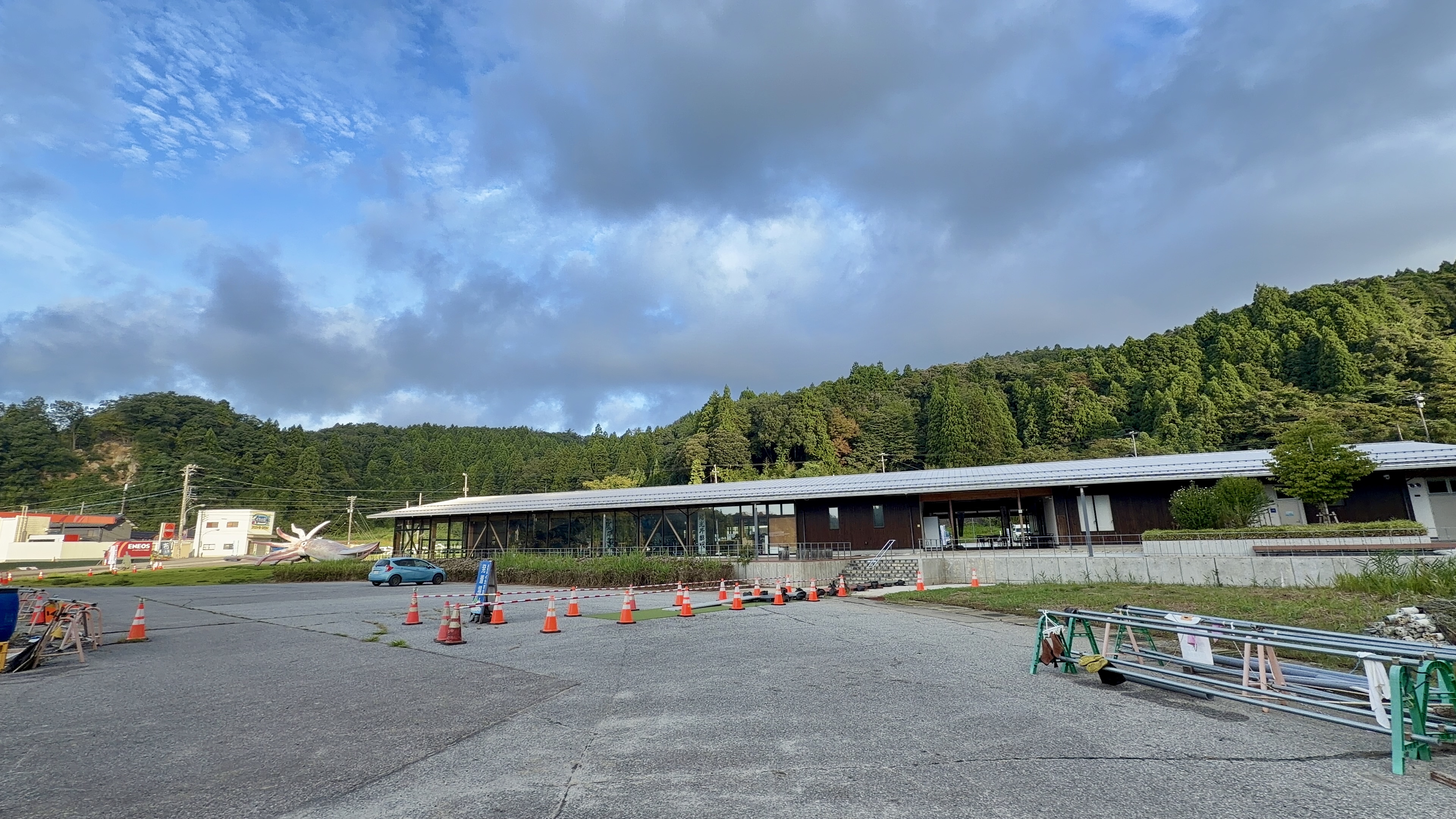 イカの駅つくモールの本館、大きな三角屋根の木造建築と駐車場、巨大イカのモニュメント