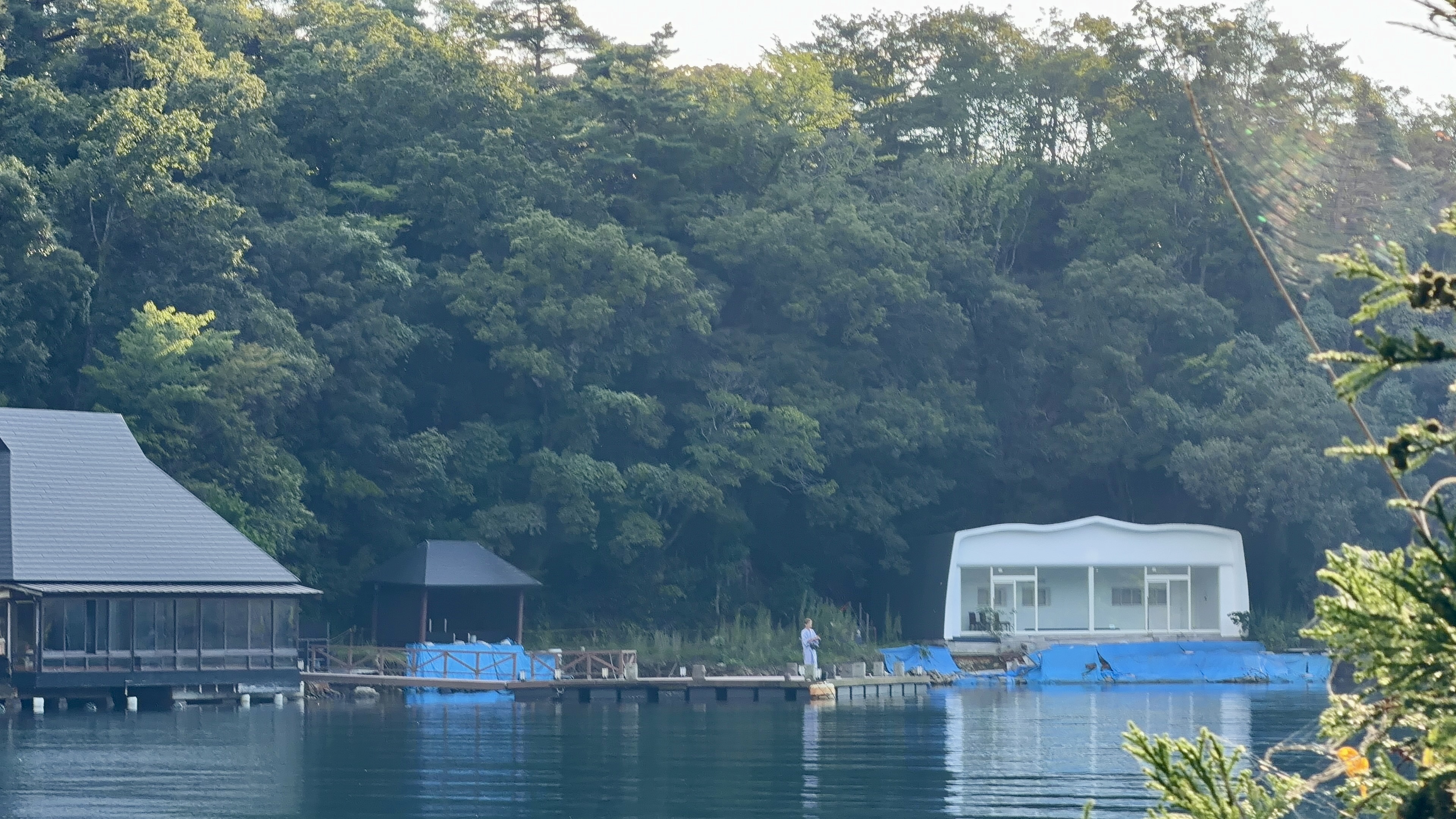 うねった白い屋根の建物、手前の桟橋には地震の被害とみられる青いブルーシートがかけられている